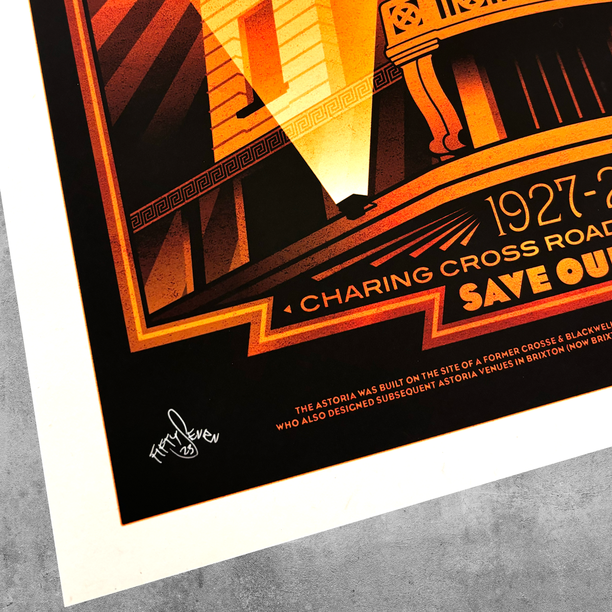 A close-up of the London Astoria ‘Red’ Poster Print – Limited Edition Of Only 50 by My Store, with warm tones, “1927–”, “Charing Cross Road,” a signature, and a brief retrospective description at the bottom on a gray textured surface.