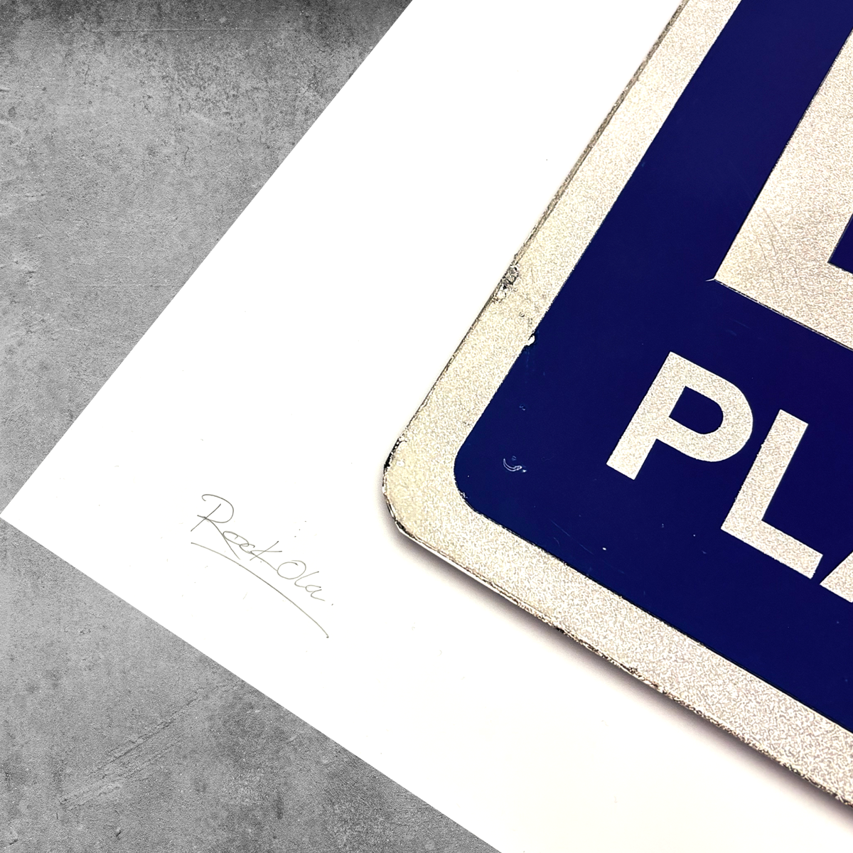 A close-up of the RocknRoad Sign Print - Exit Planet Dust from My Store, a limited edition of 25, shows the blue parking sign on a white paper signed Rett Ole—perfect for collectors seeking unique art.