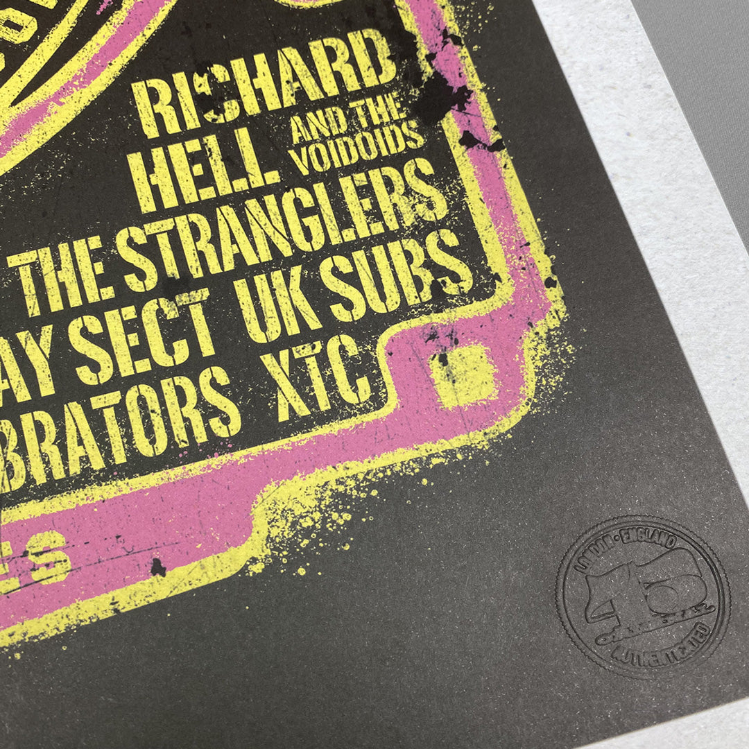A close-up of the Rainbow Punk Poster Print - Limited Edition of Only 100 from My Store, with distressed yellow text on black and pink featuring bands like Richard Hell and XTC, plus a circular embossed logo in the bottom right corner.
