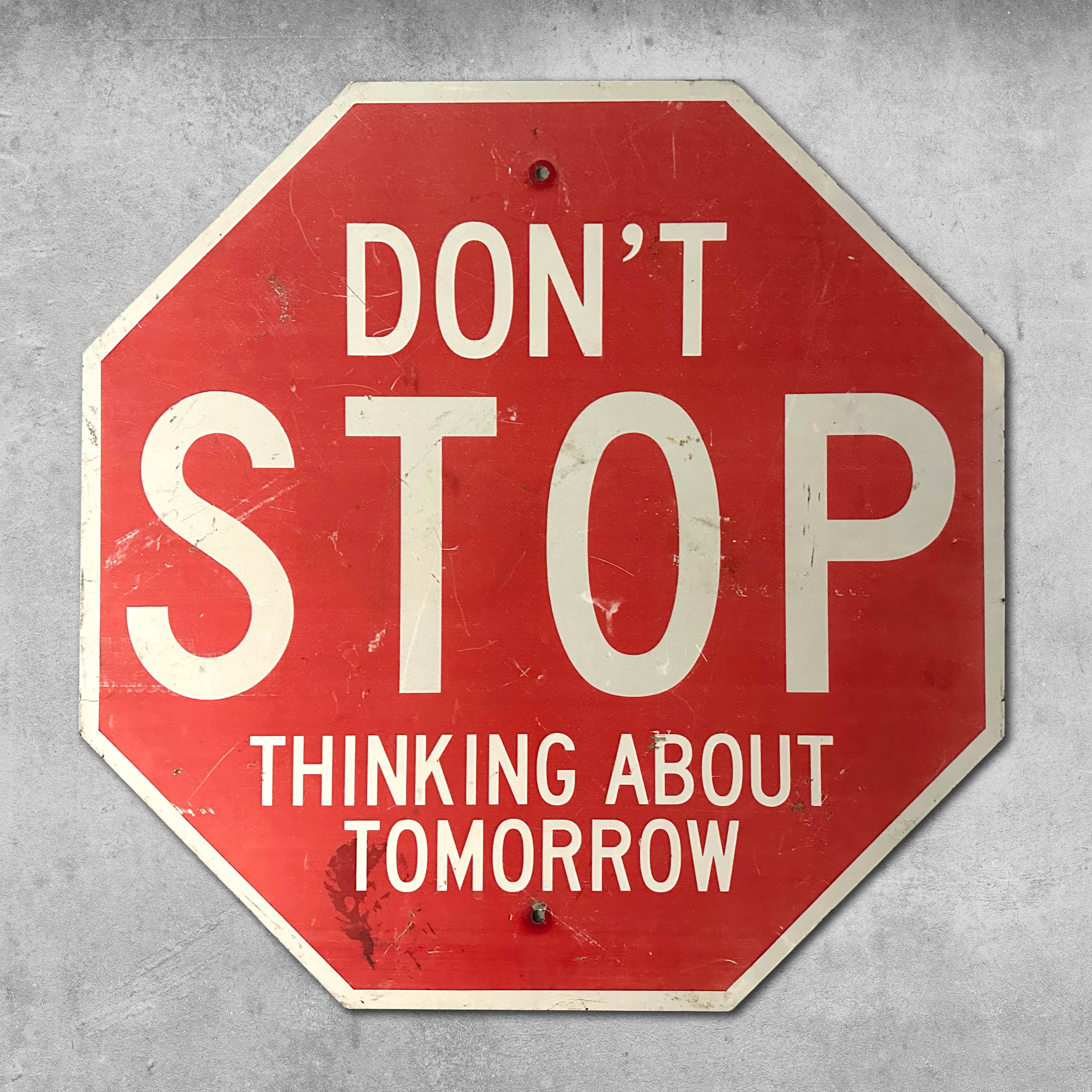 The Original RocknRoad Sign - Dont Stop Thinking About Tomorrow by My Store features a red, octagonal design with bold white text—a standout accent for any man cave against a gray, textured backdrop.