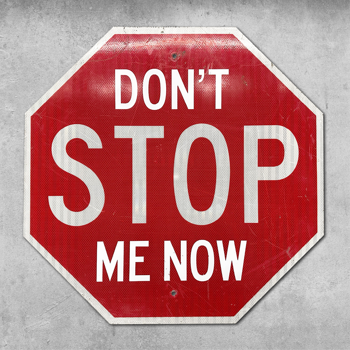 The Original RocknRoad Sign - Dont Stop Me Now by 45 Original is a red, octagonal metal sign with DONT STOP ME NOW in white, adding a fun twist to classic British street style against a concrete background.