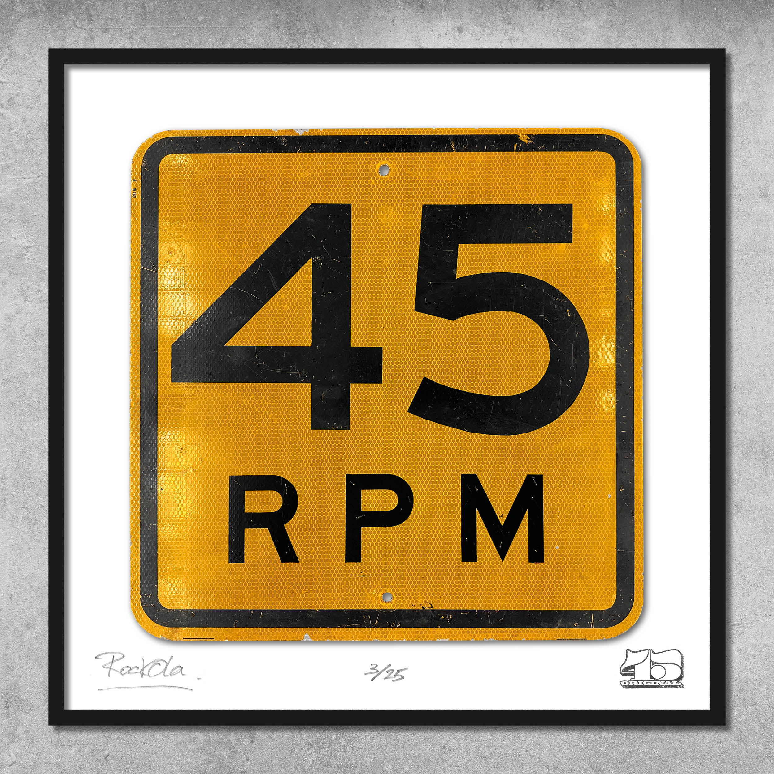 The RocknRoad Sign Print - 45 RPM US by My Store is a framed giclée print showing a yellow speed limit sign with 45 RPM in bold black text on a textured background, limited to 25 editions and displayed on a gray wall.